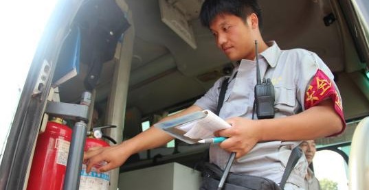 安檢員檢查長途客車內(nèi)的滅火器圖